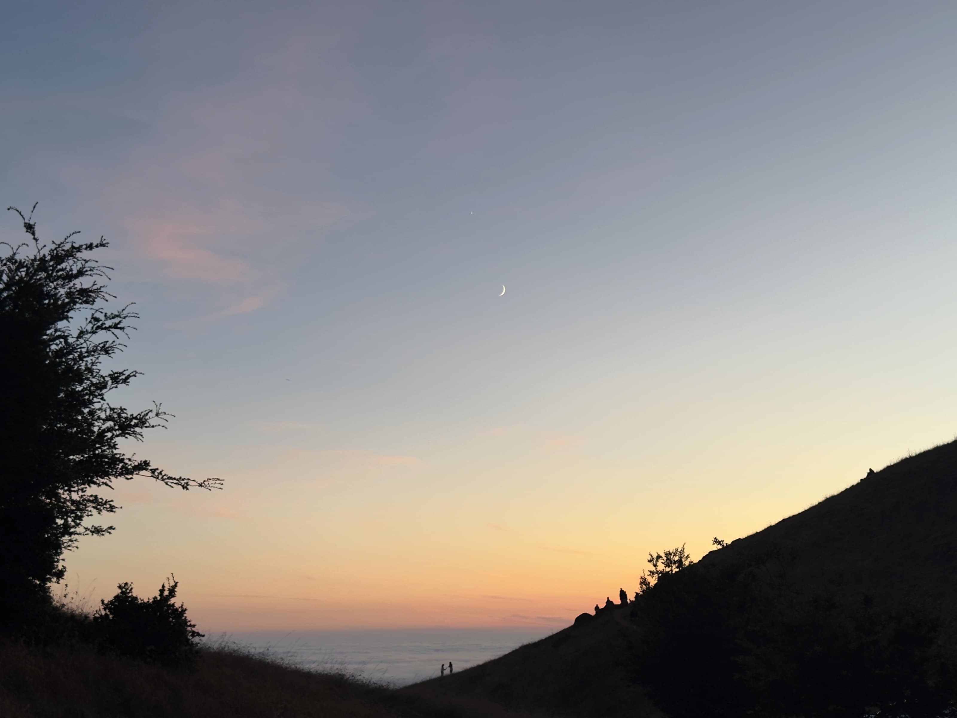 A crescent moon over Trojan Point after sunset.