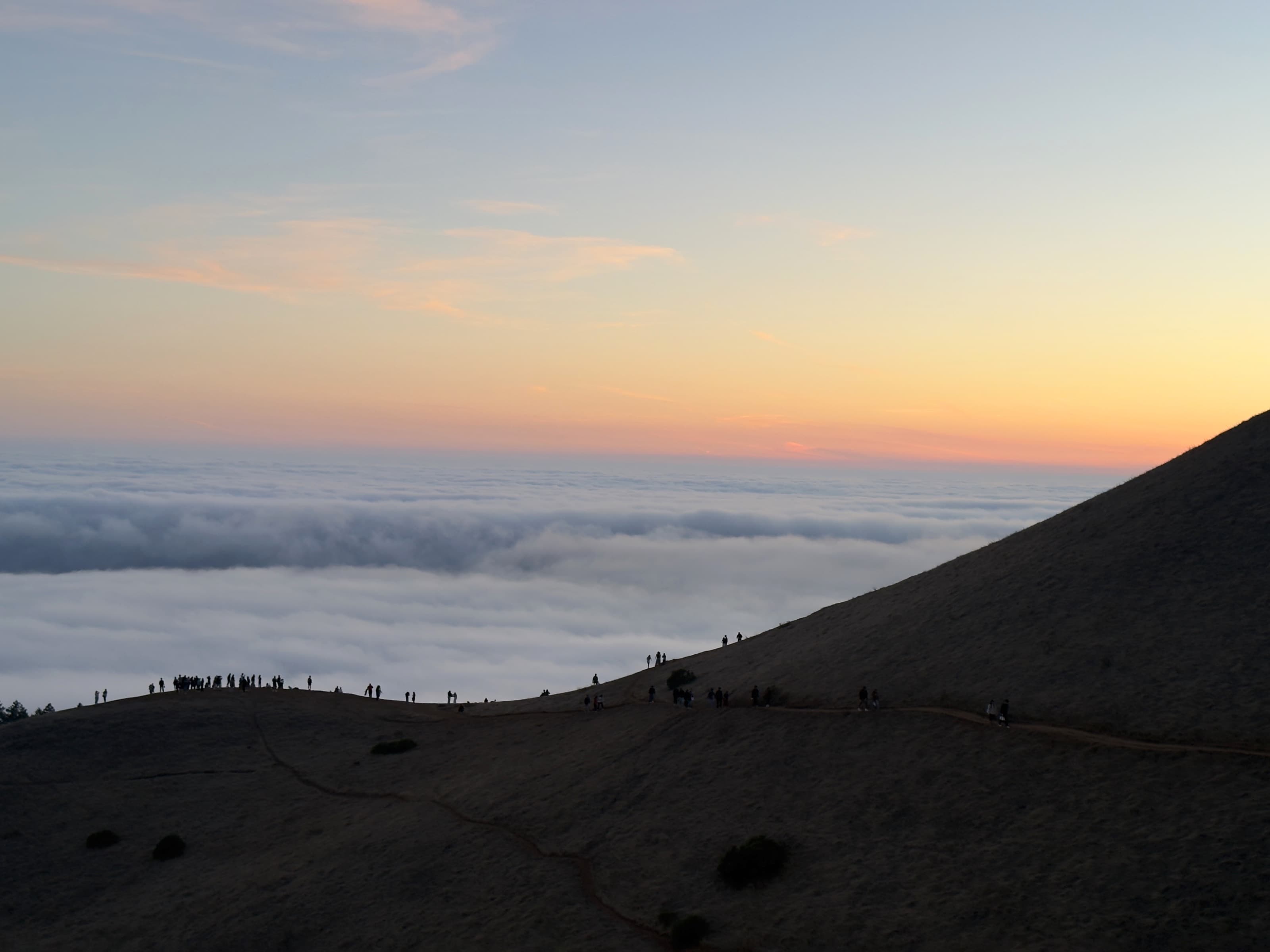 Sunset watchers silhouetted above the marine layer at Trojan Point.